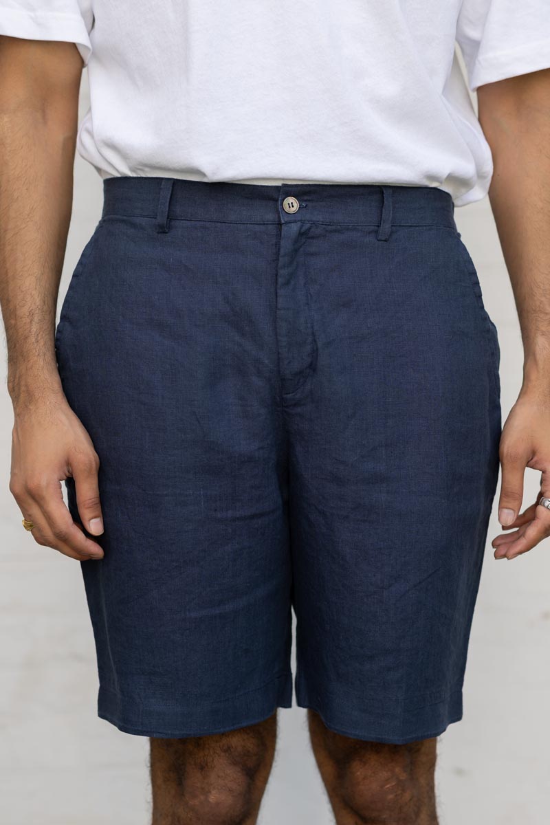 Person wearing Navy Blue Shorts and a white shirt against a plain background