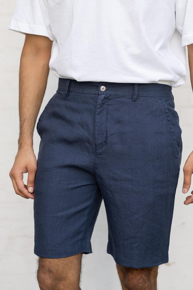 Person wearing Navy Blue Shorts and a white shirt against a plain background