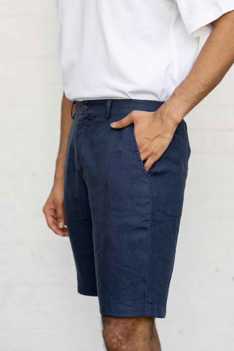 Person wearing Navy Blue Shorts and a white shirt against a plain background