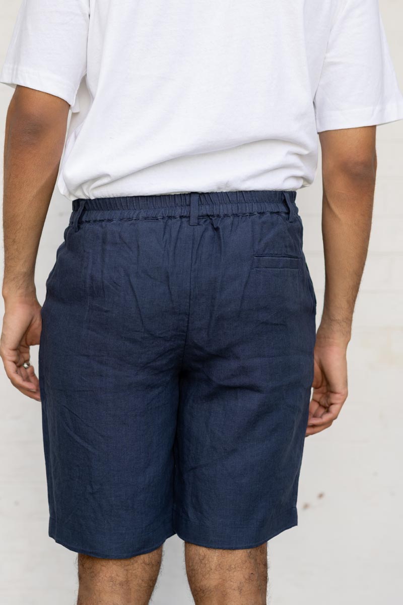 Person wearing Navy Blue Shorts and a white t-shirt against a plain background