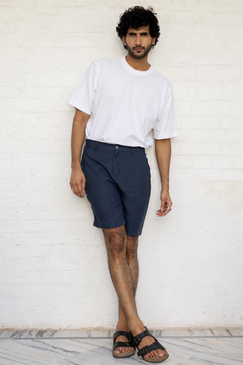 Man wearing a white t-shirt and Navy Blue Shorts against a light background