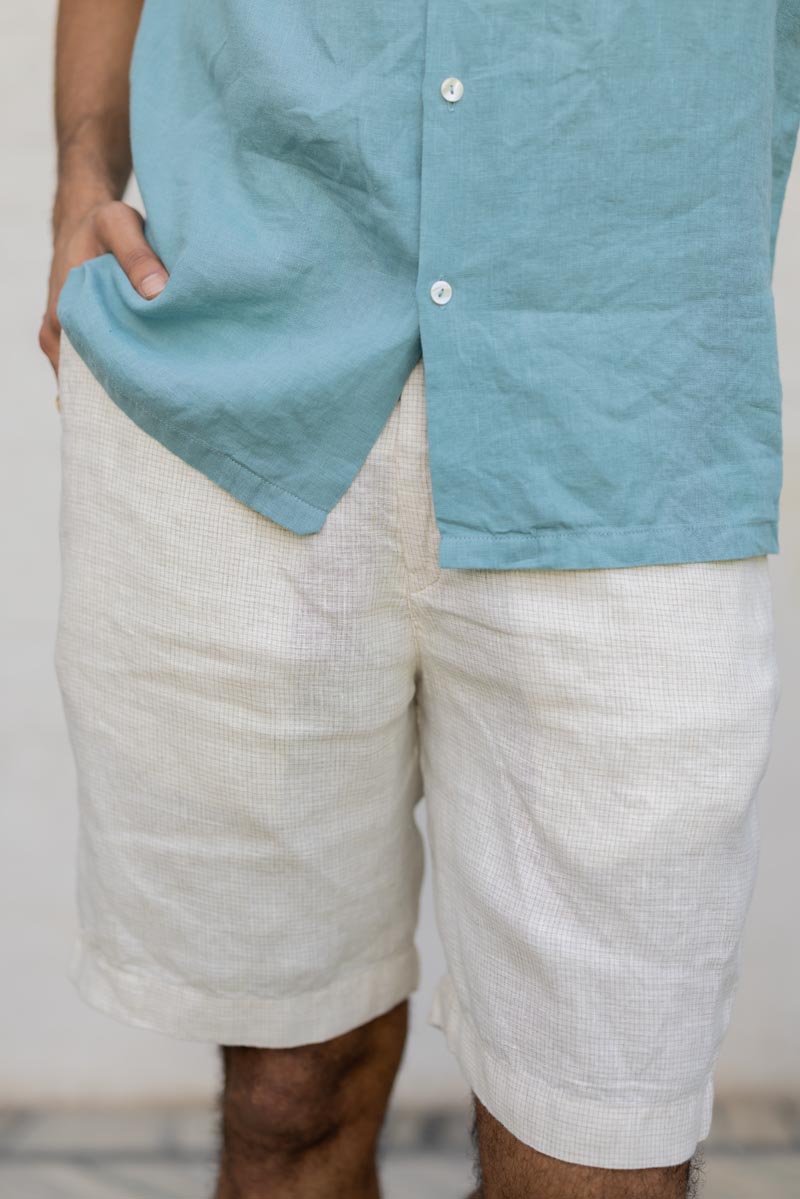 Person wearing a lIvory Check Shorts and white shorts against a neutral background