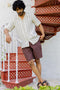 Man Wearing Cuban Collar Shirt Beige Cabana Stripe and standing on a red staircase wearing a striped shirt and brown shorts.