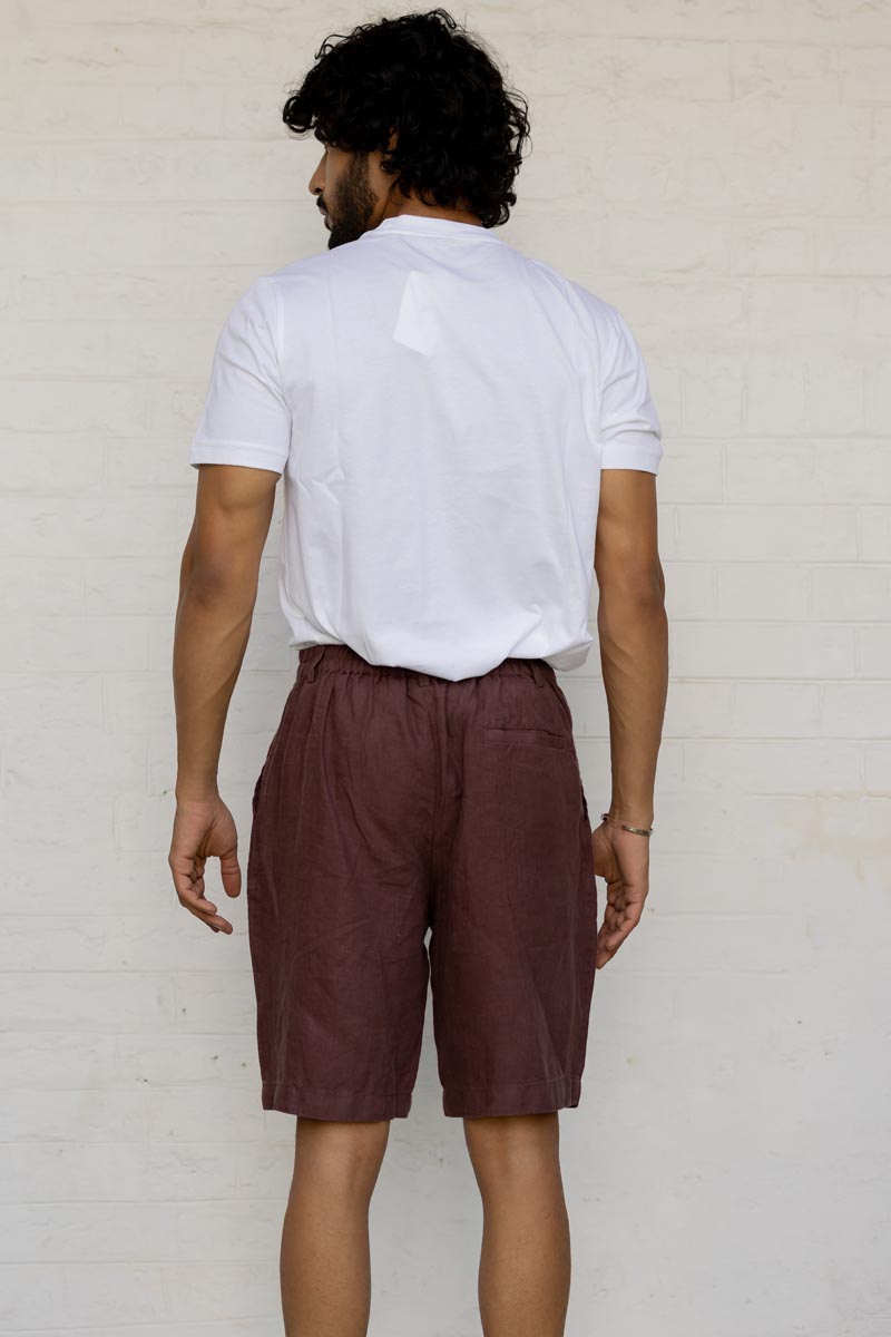 Man wearing a white shirt and Wine Shorts against a light background