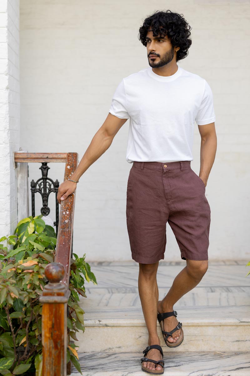Man wearing a white t-shirt and Wine Shorts standing on a staircase.