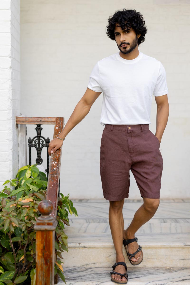 Man wearing a white t-shirt and Wine Shorts standing on a staircase.
