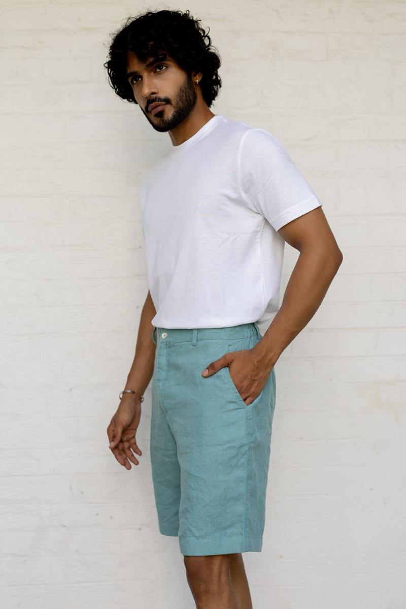 Man wearing a white t-shirt and Pine Green Shorts against a plain background