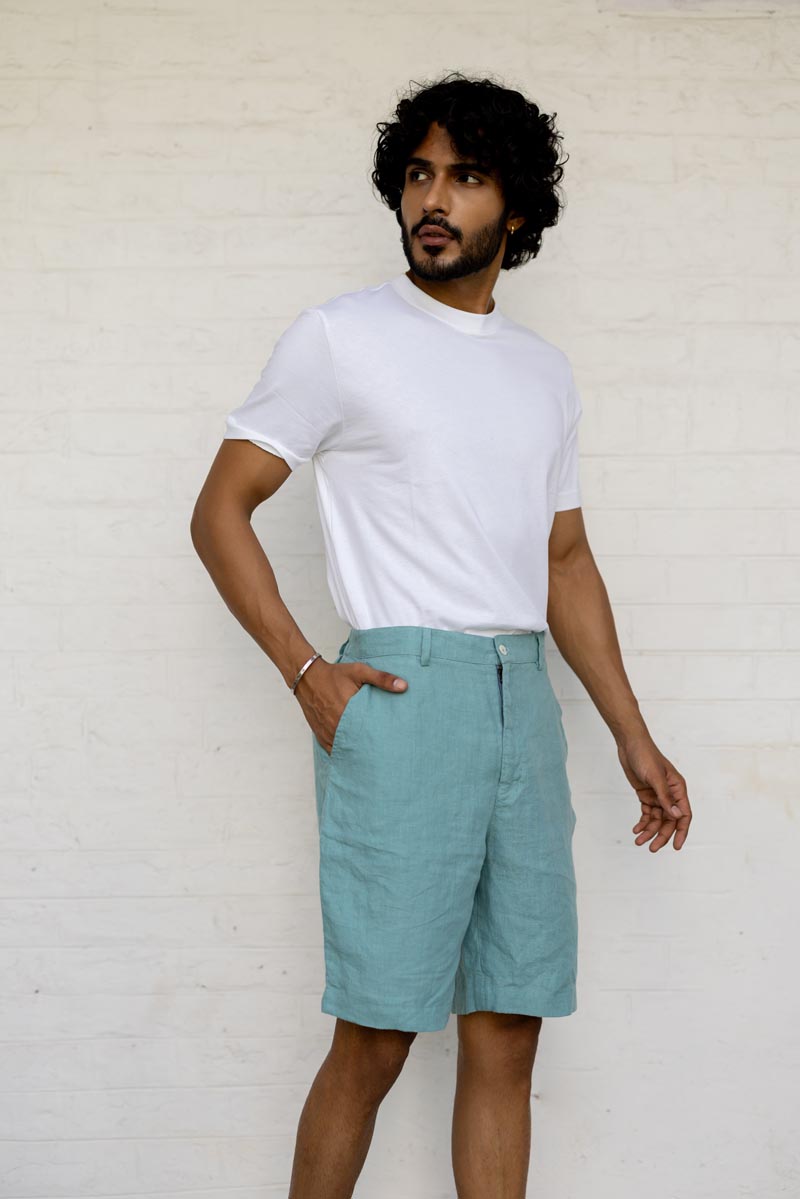 Man wearing a white t-shirt and Pine Green Shorts against a white wall