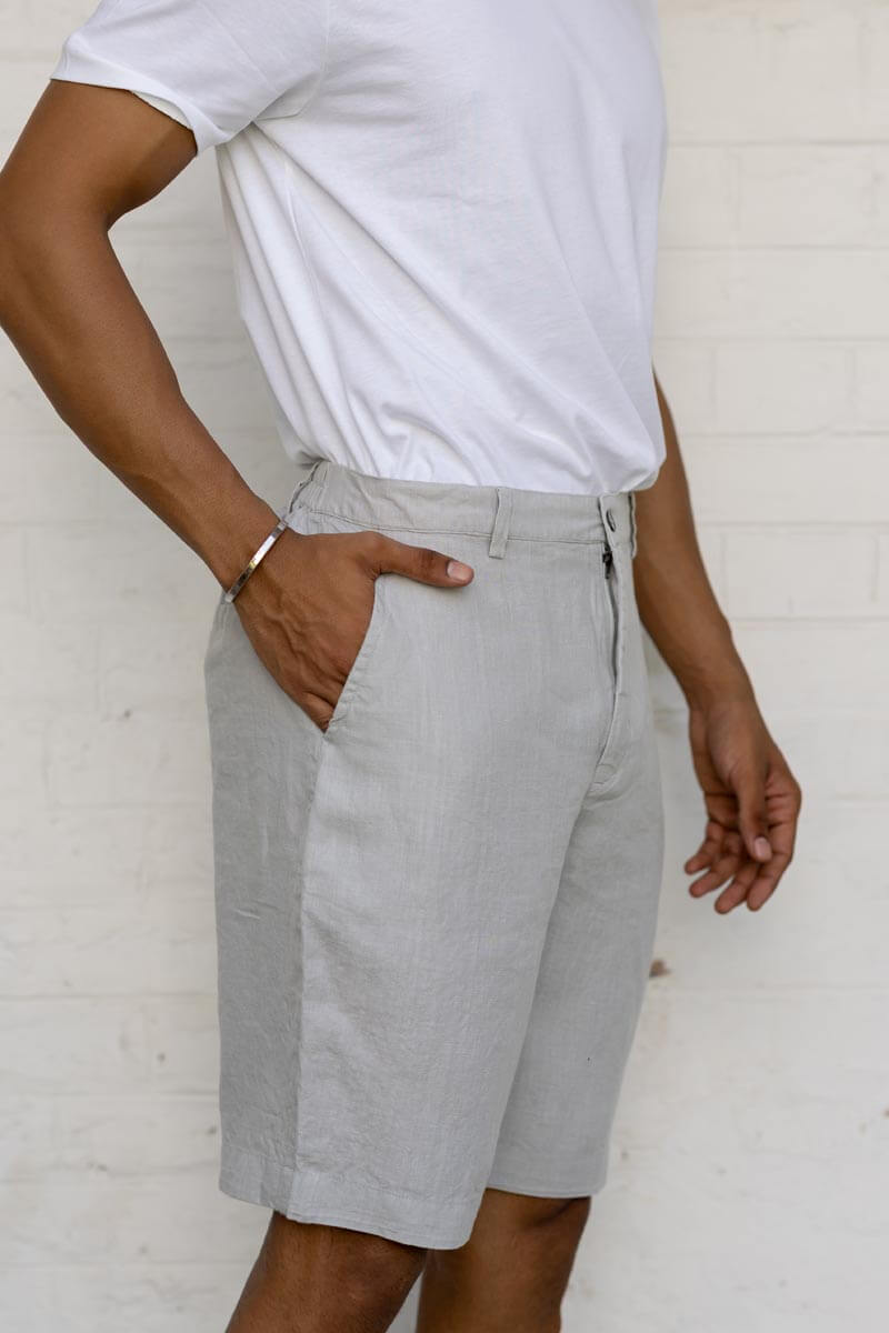 Person wearing light gray shorts and a Cloud Grey Shorts against a white brick wall.