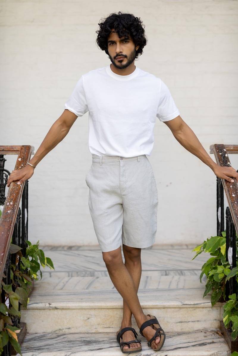 Man wearing a white t-shirt and Cloud Grey Shorts standing on a marble staircase.