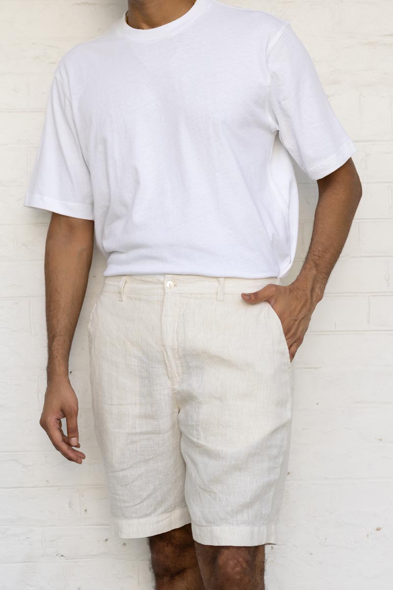 Person wearing a white t-shirt and Ivory Fine Stripe Shorts against a white brick wall.