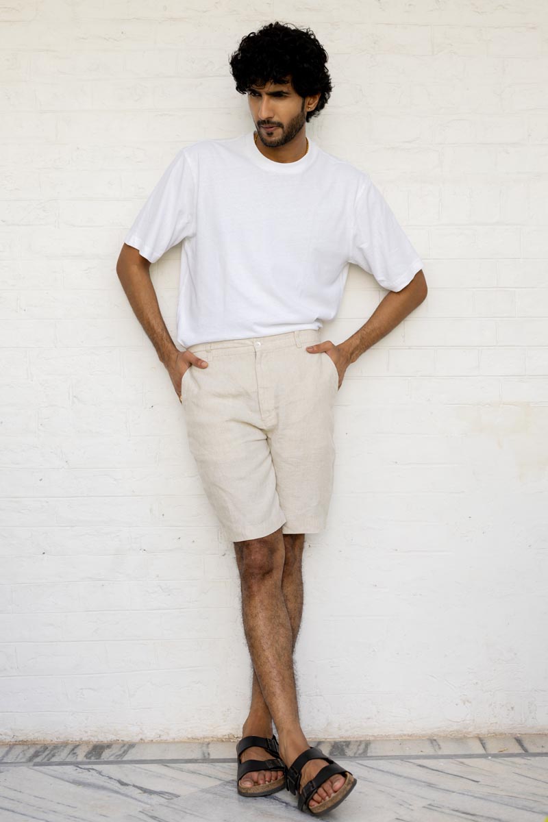 Man wearing a white t-shirt and Classic Cream Shorts against a white wall.