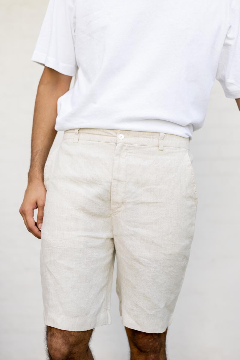 Person wearing a white t-shirt and beige shorts on a plain background