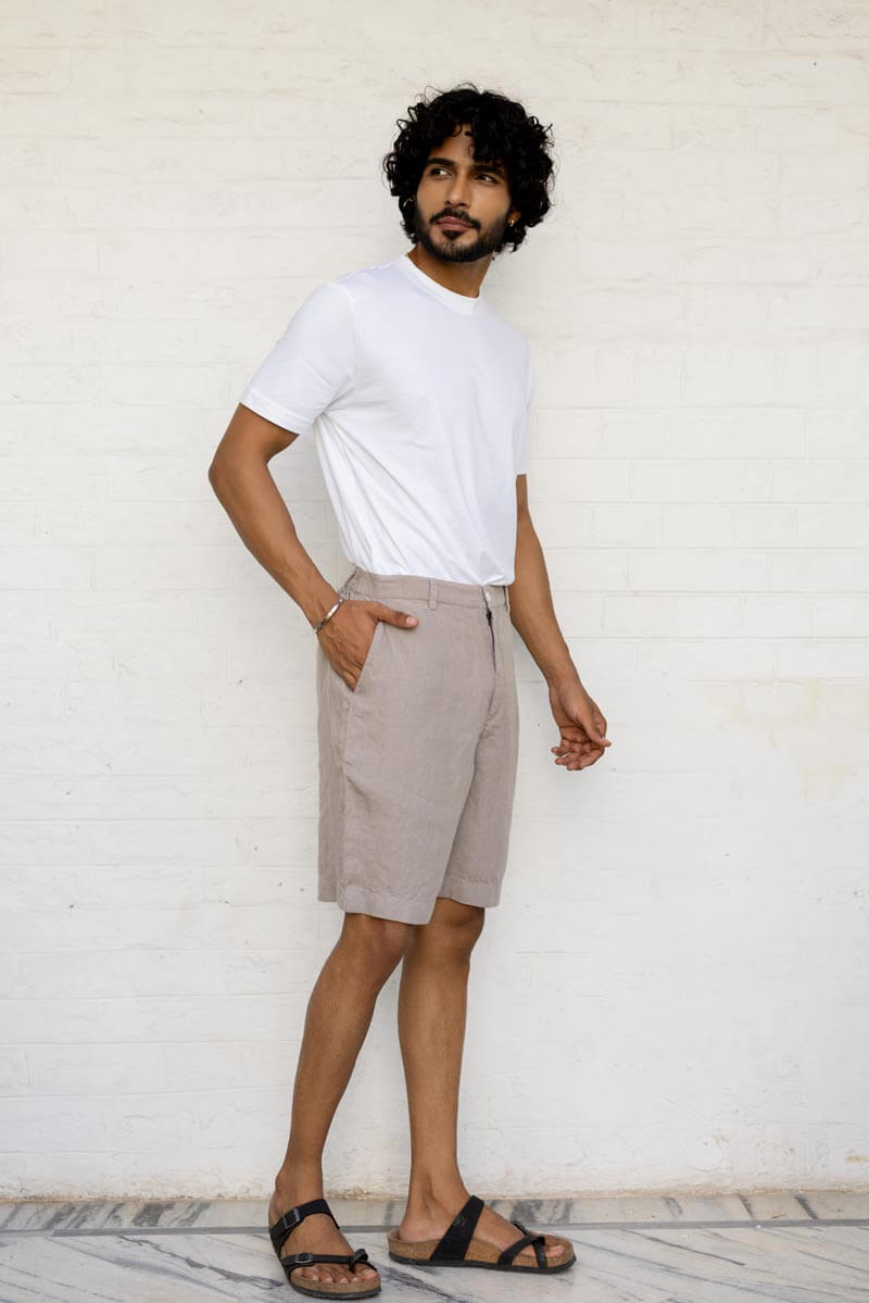 Man wearing a white t-shirt and Almond Beige Shorts against a white wall.