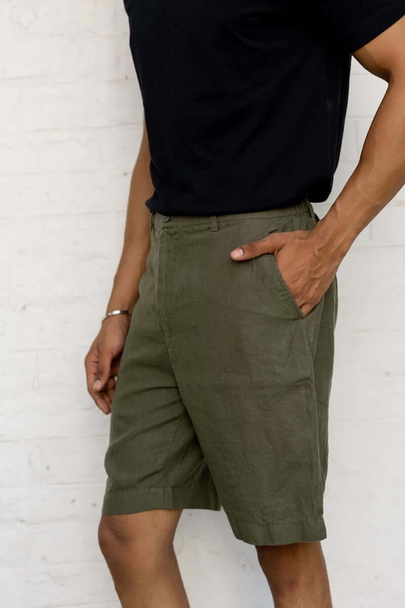 Person wearing Crocodile Green Shorts and a black shirt against a white brick wall.