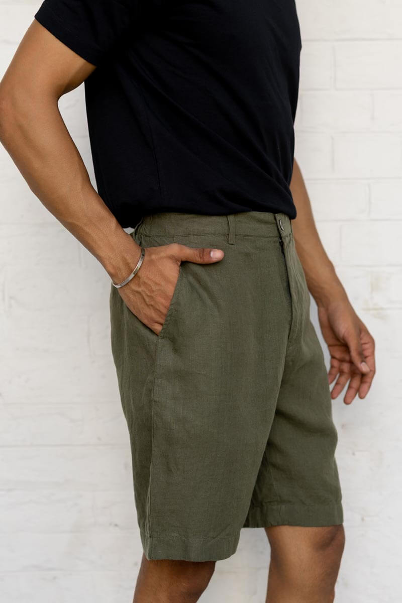 Person wearing Crocodile Green Shorts and a black shirt against a white brick wall.