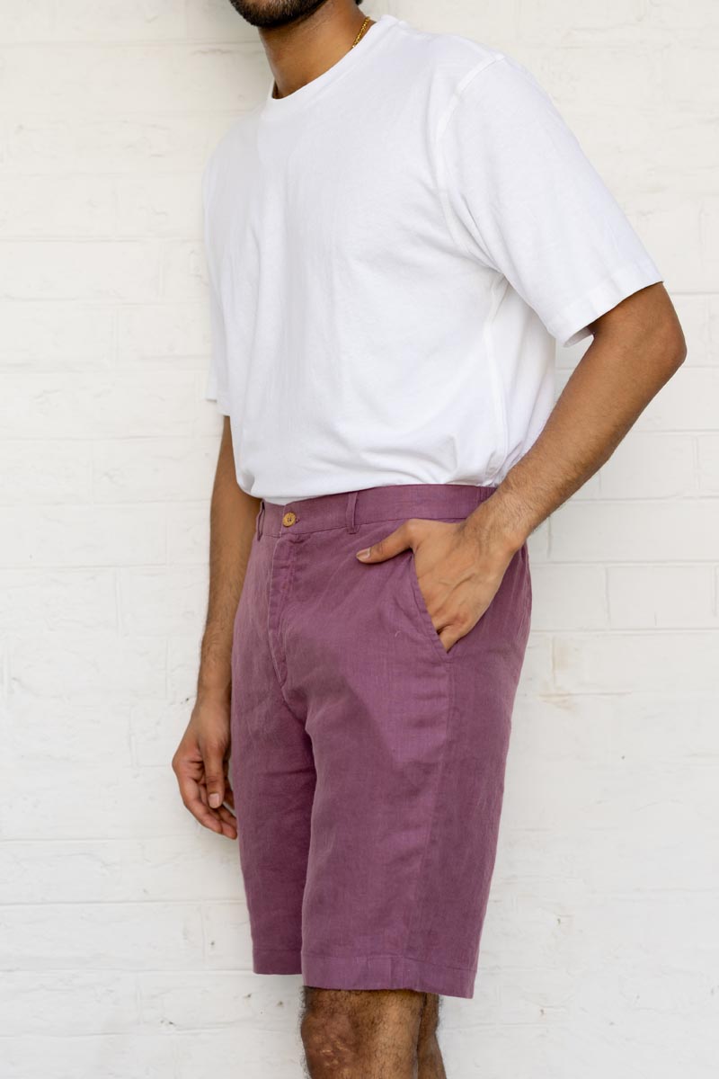 Person wearing a white t-shirt and Twilight Purple Shorts against a white brick wall.