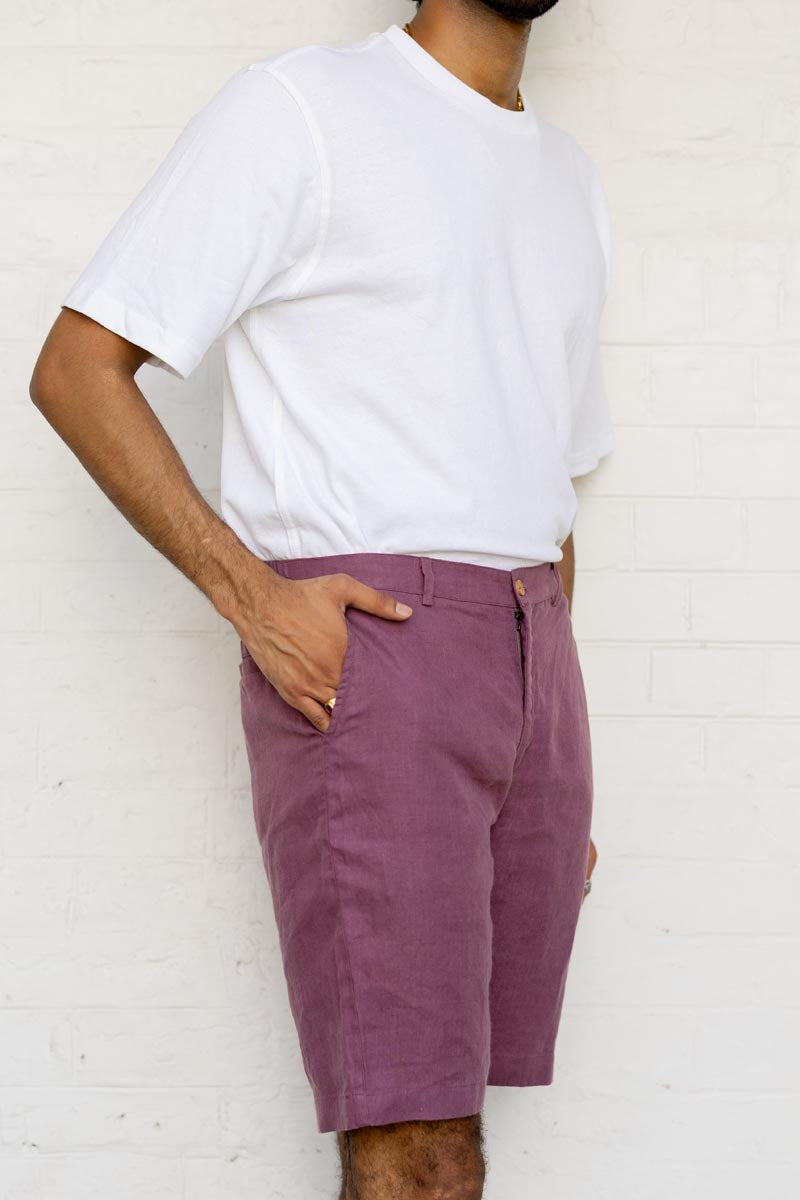 Person wearing a white t-shirt and Twilight Purple Shorts against a white brick wall.