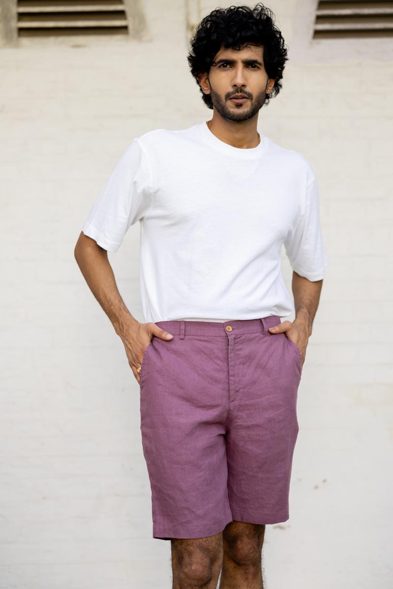 Man wearing a white t-shirt and Twilight Purple Shorts standing against a light-colored wall.