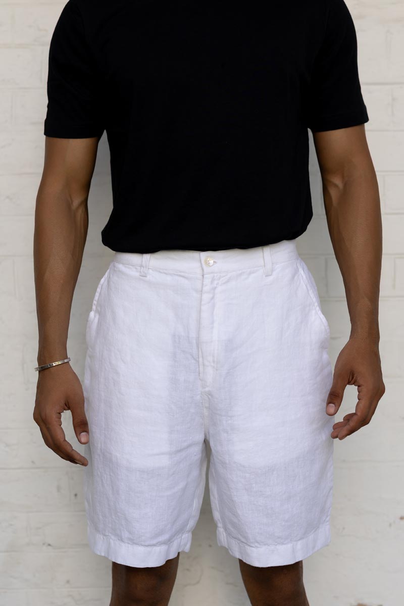 Person wearing a black t-shirt and White Shorts against a light wooden panel background