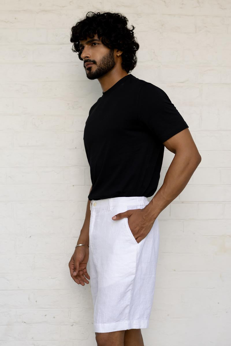 Man wearing a black t-shirt and White Shorts against a light-colored wall