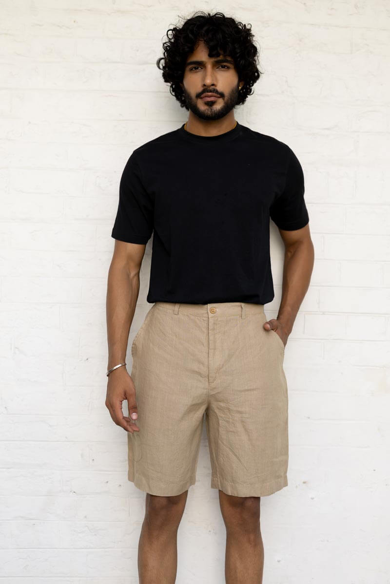 Man wearing a black t-shirt and Desert Sand Shorts against a white wall