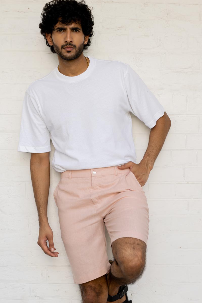 Man wearing a white t-shirt and Flamingo Shorts  against a white brick wall.