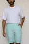 Man wearing a white t-shirt and Celestial Green Shorts against a plain background