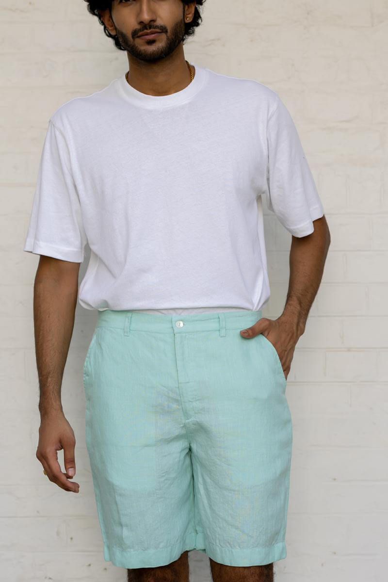 Man wearing a white t-shirt and Celestial Green Shorts against a plain background