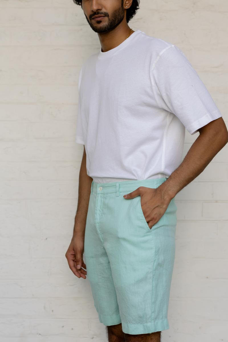 Man wearing a white t-shirt and Celestial Green Shorts against a plain background