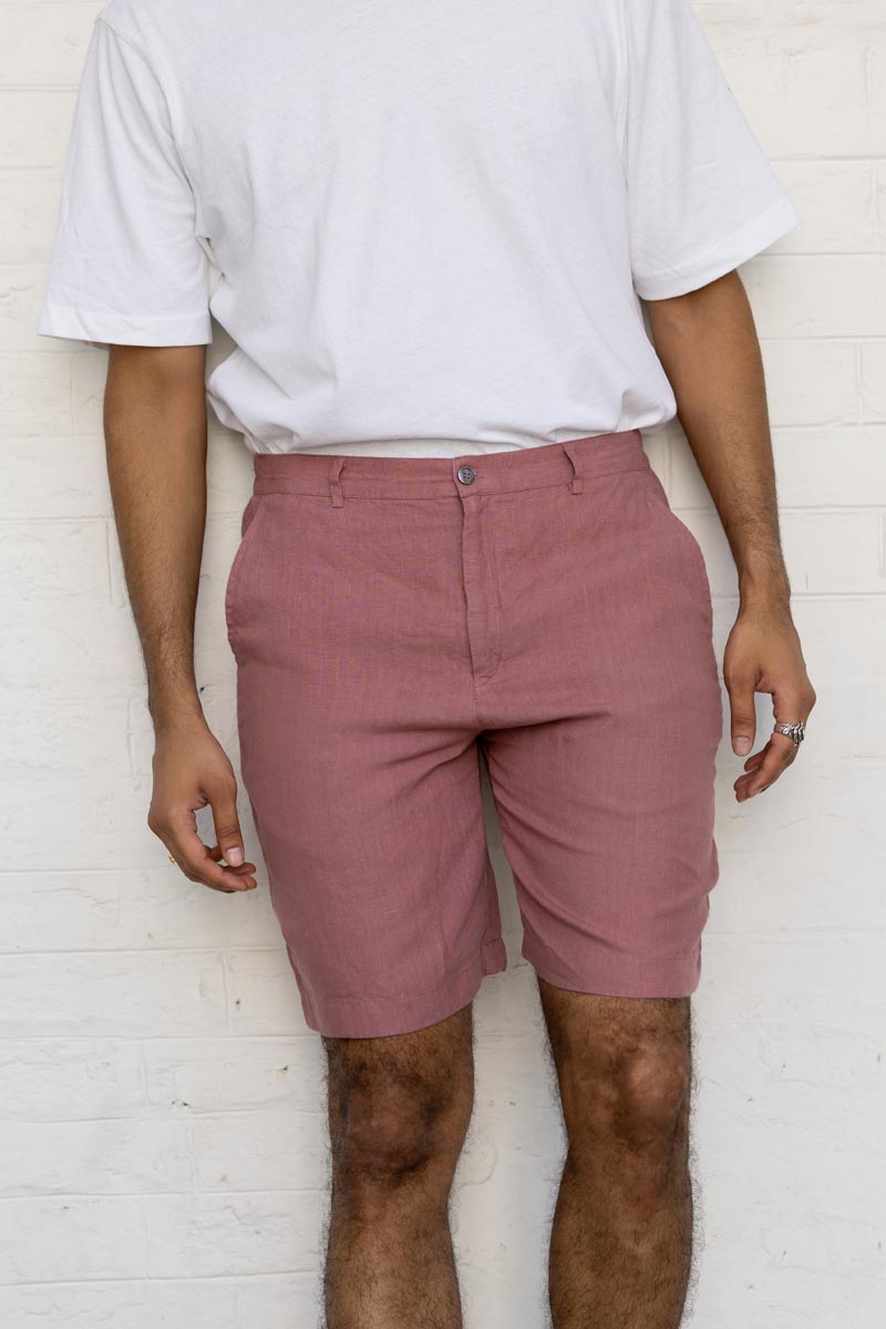 Person wearing Rose Gold Shorts and a white t-shirt against a white brick wall.