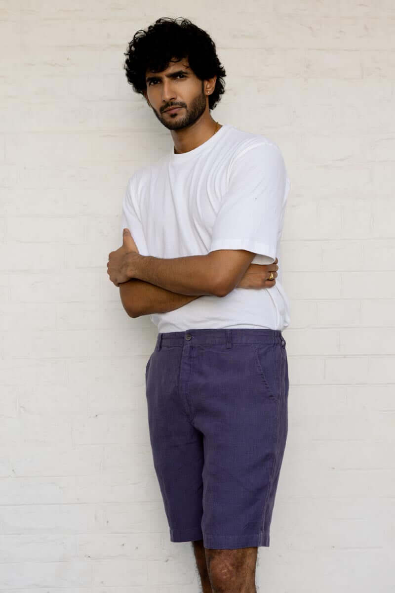 Man wearing a white t-shirt and Blueberry Shorts standing against a light-colored wall.